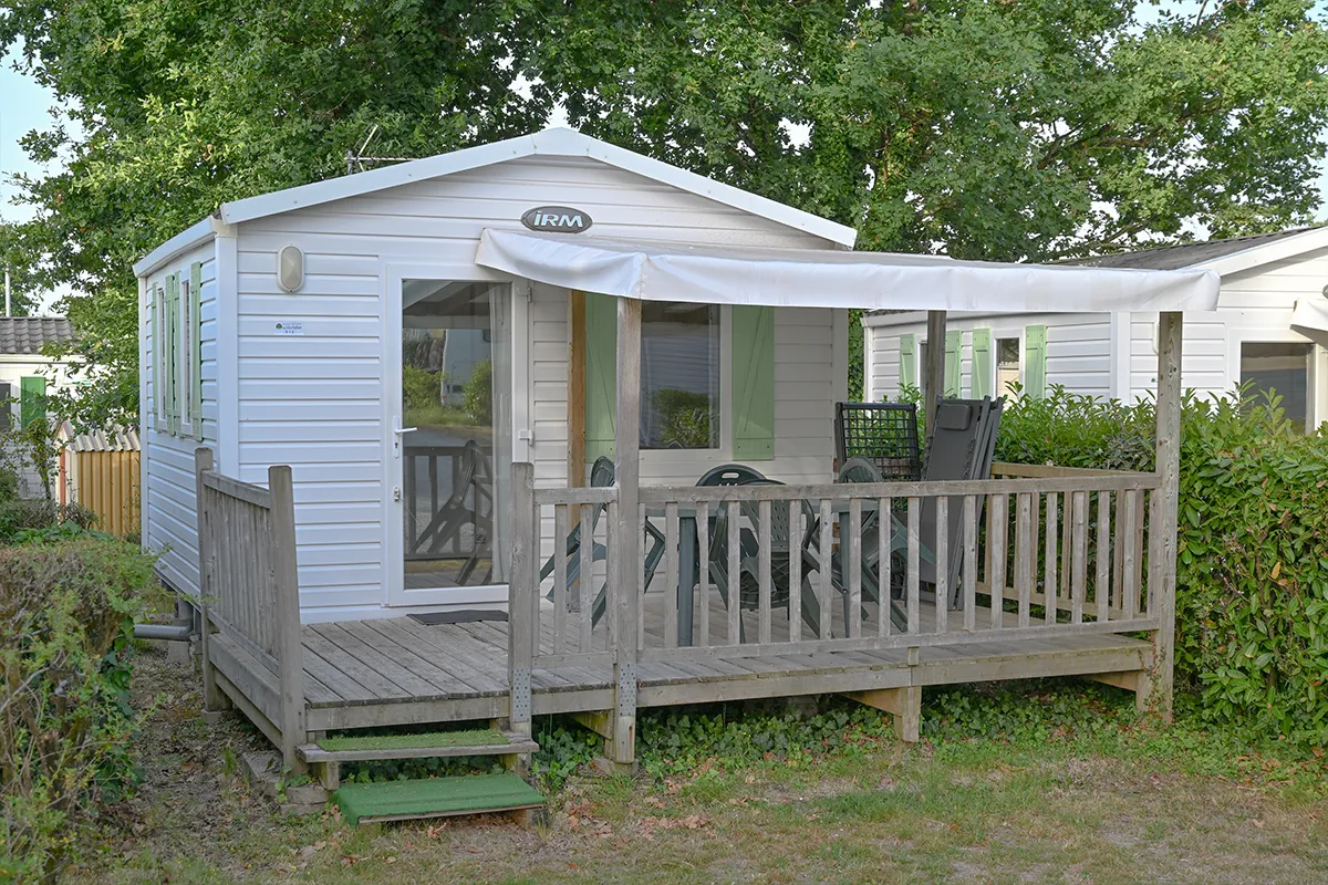 Mobil-home compact et sa terrasse en bois semi-couverte au camping à Ambon