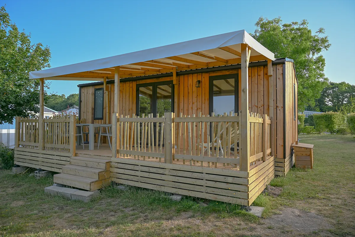 Grandes baies vitrées et terrasse couverte d'un mobil-home premium du camping Domaine du Morbihan
