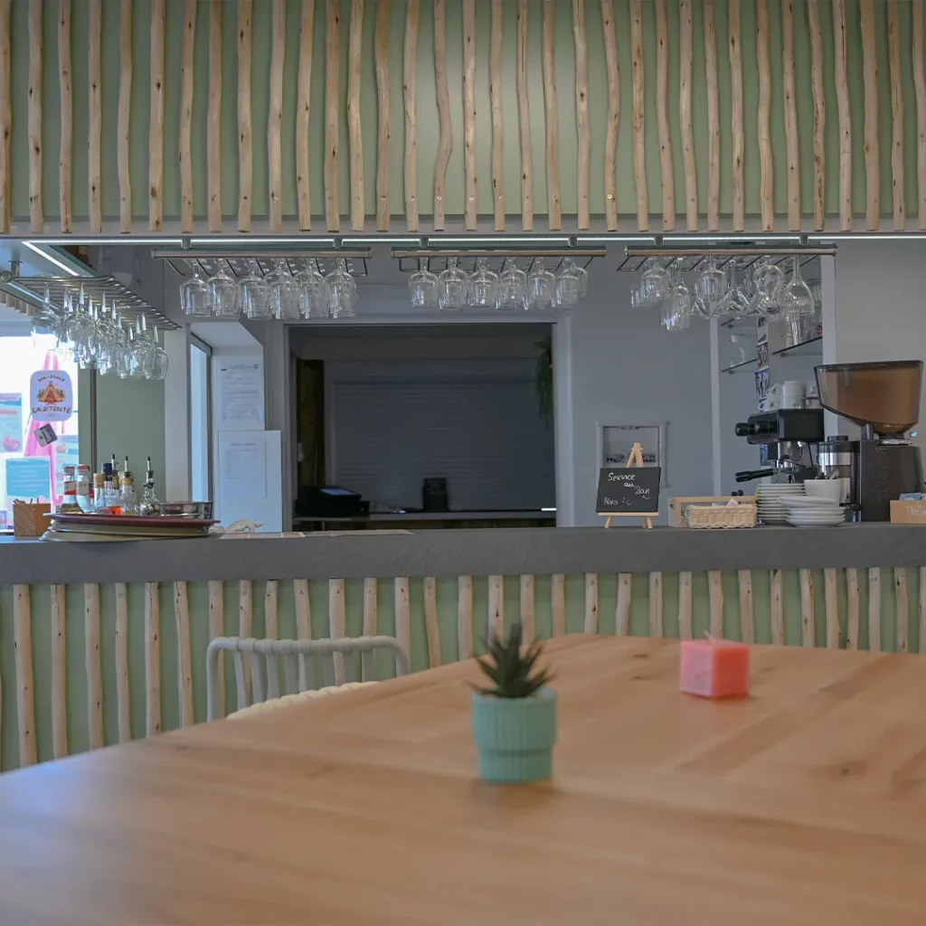 Verres suspendus et machine à café derrière le comptoir du bar habillé de bois flotté