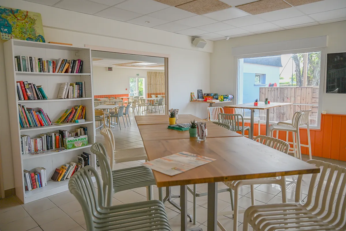 Coin bibliothèque et tablées de la salle commune attenante au snack, au camping à Ambon