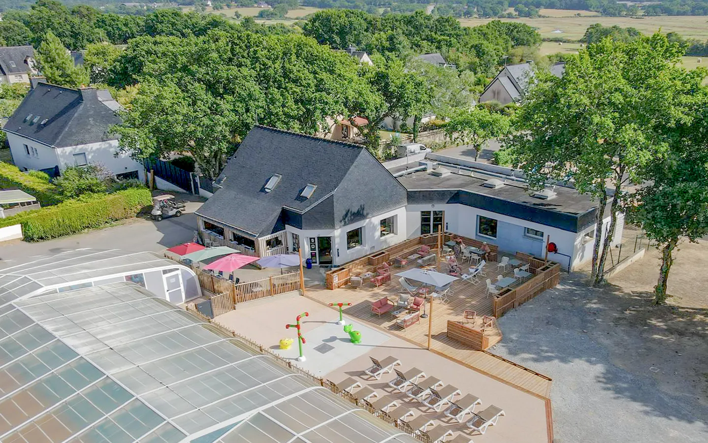 Le camping vu du ciel : terrasse en bois, transats et jeux d'eau à Ambon